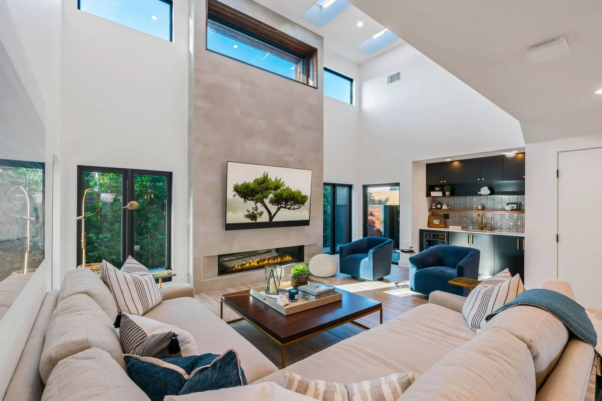 Double-height great room with tile-clad fireplace wall, clerestory windows, sectional and loft above